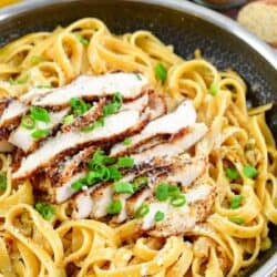 Pasta with lemon pepper chicken over top in a pan.