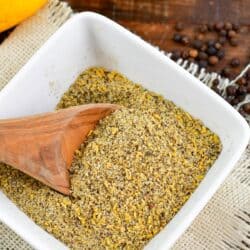 Lemon pepper seasoning in a bowl with a wooden spoon.