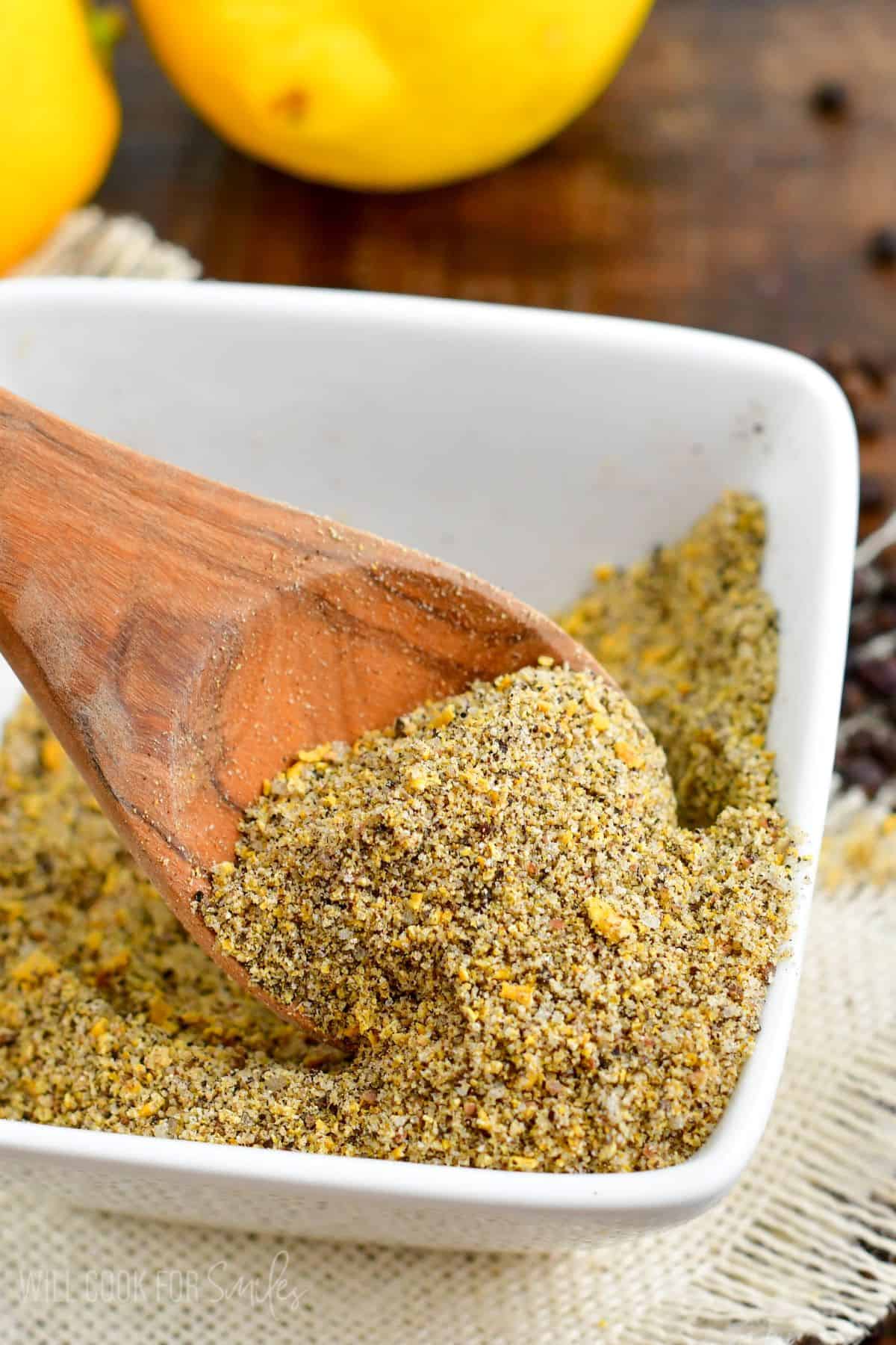 lemon pepper seasoning in a bowl scooping up some of the seasoning.