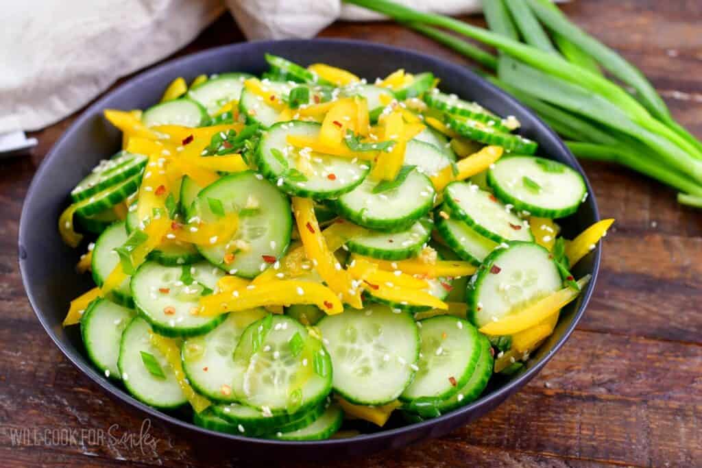 Asian cucumber salad in a serving bowl on a wood surface.