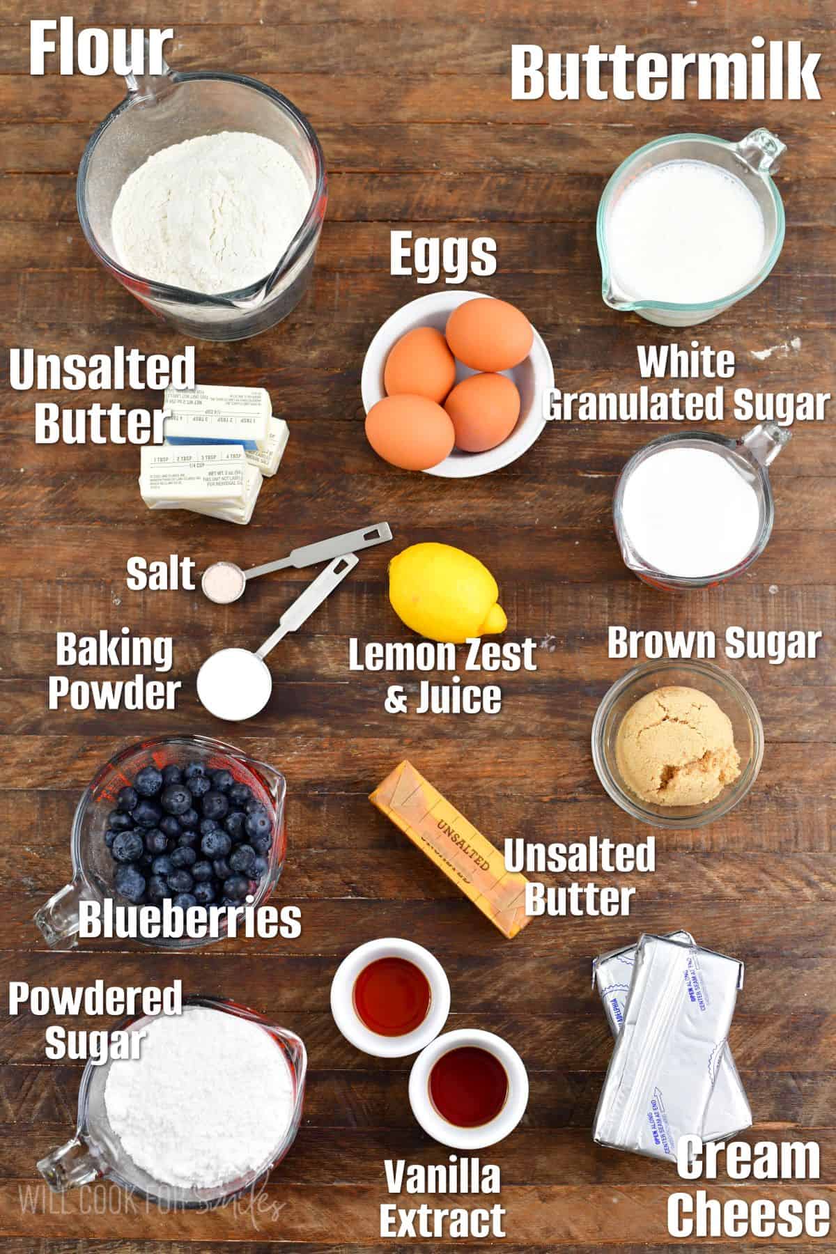 Labeled ingredients for blueberry cake on a wood cutting board.