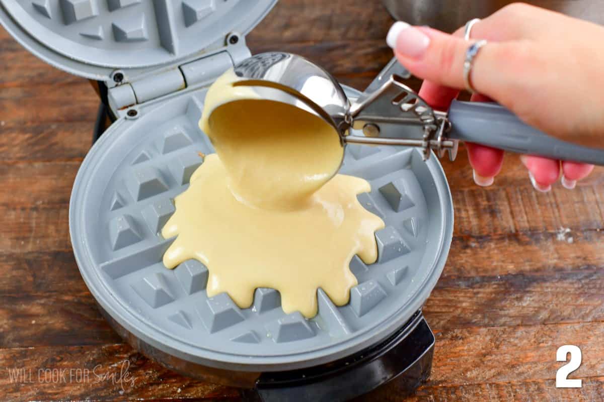 scooping some waffle batter onto the waffle maker using ice cream scoop.