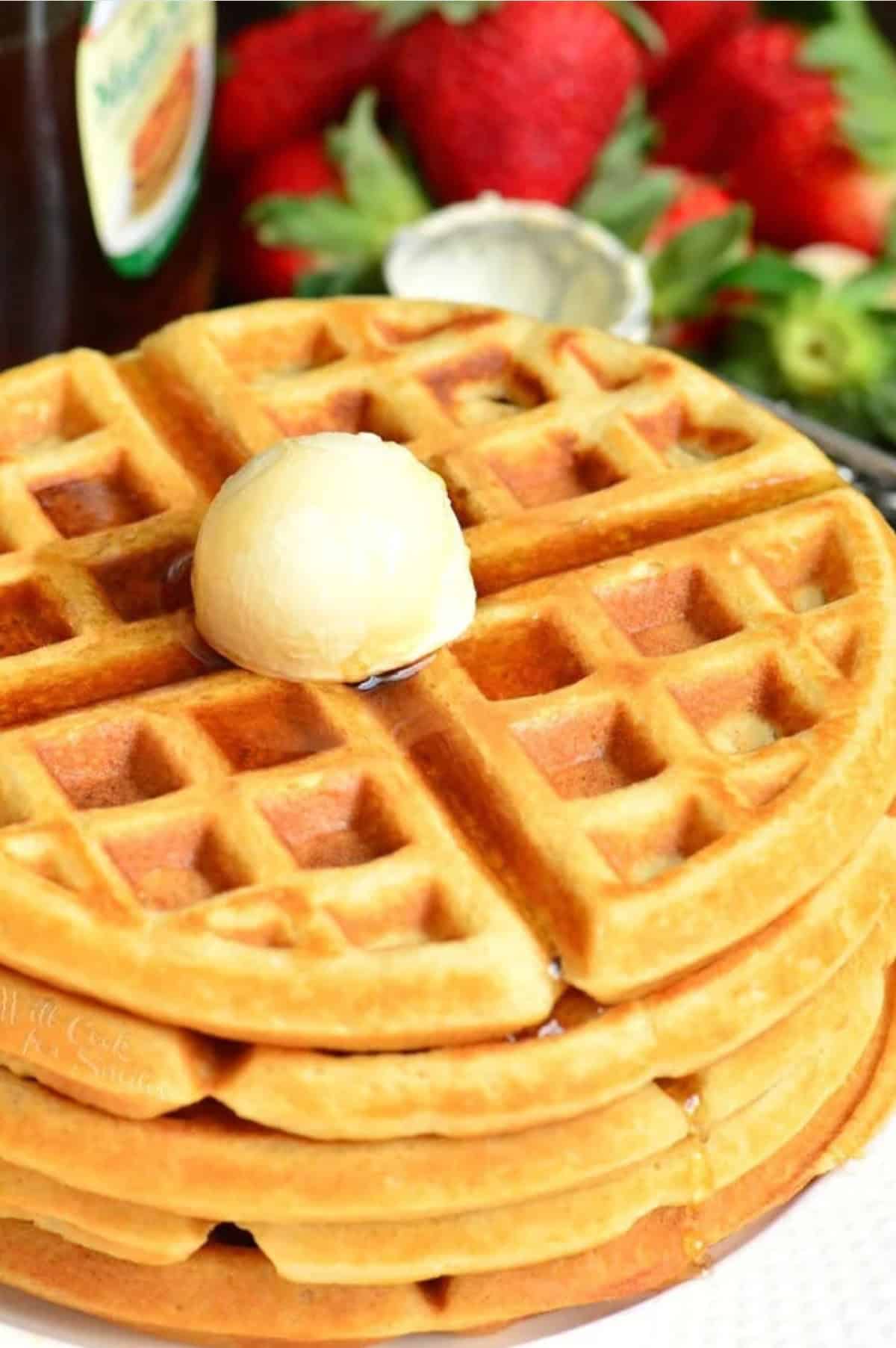 buttermilk waffles on a plate with butter on top and syrup.