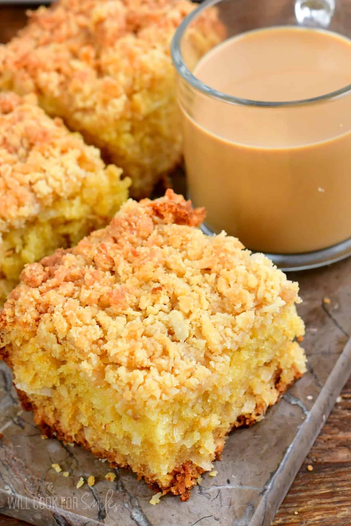 three slices of coconut coffee cake with a glass mug of coffee next to them.