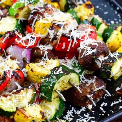 Italian vegetables grilled and topped with parmesan cheese on a baking sheet.
