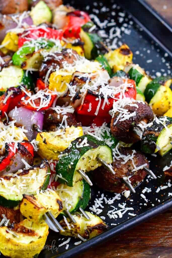 Italian vegetables grilled and topped with parmesan cheese on a baking sheet.