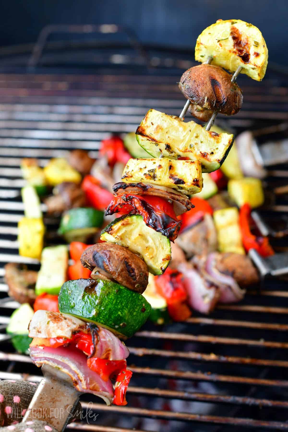 Holding a skewer with cooked Italian grilled vegetables.