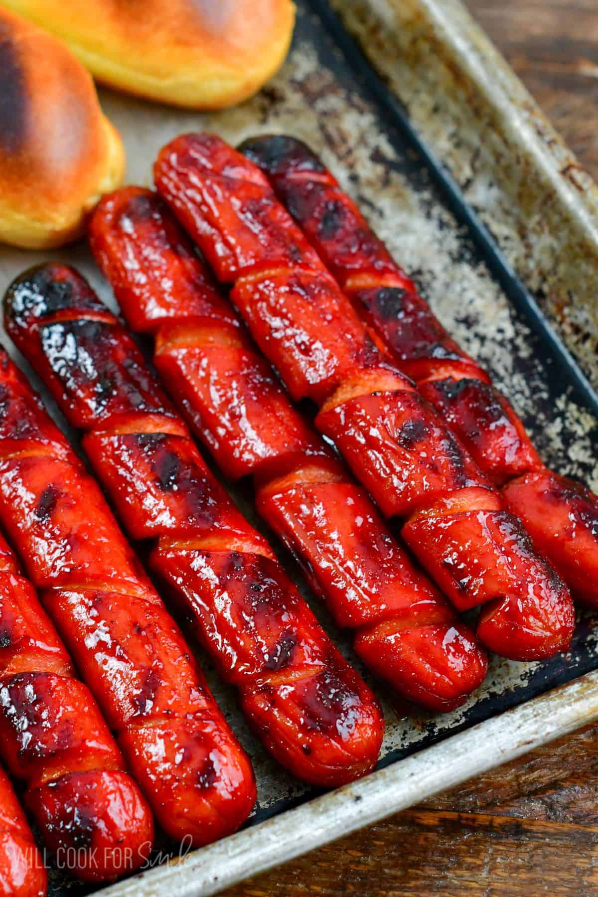 Cooked Sriracha Honey Hot Dogs and buns on a metal tray.