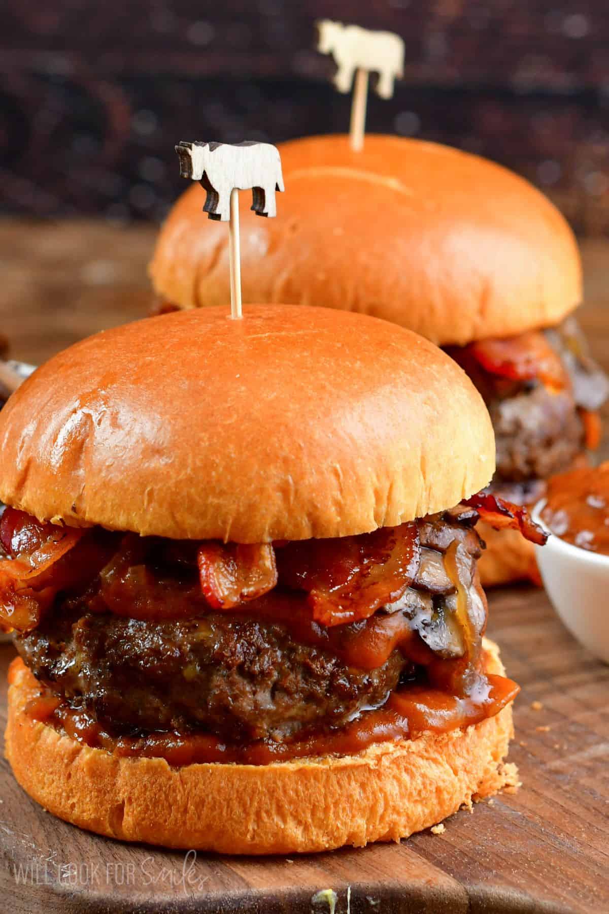 Two burgers with sauteed mushrooms, bacon, and whiskey sauce on a bun.