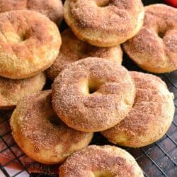 apple pie donuts piled up on a wire rack.