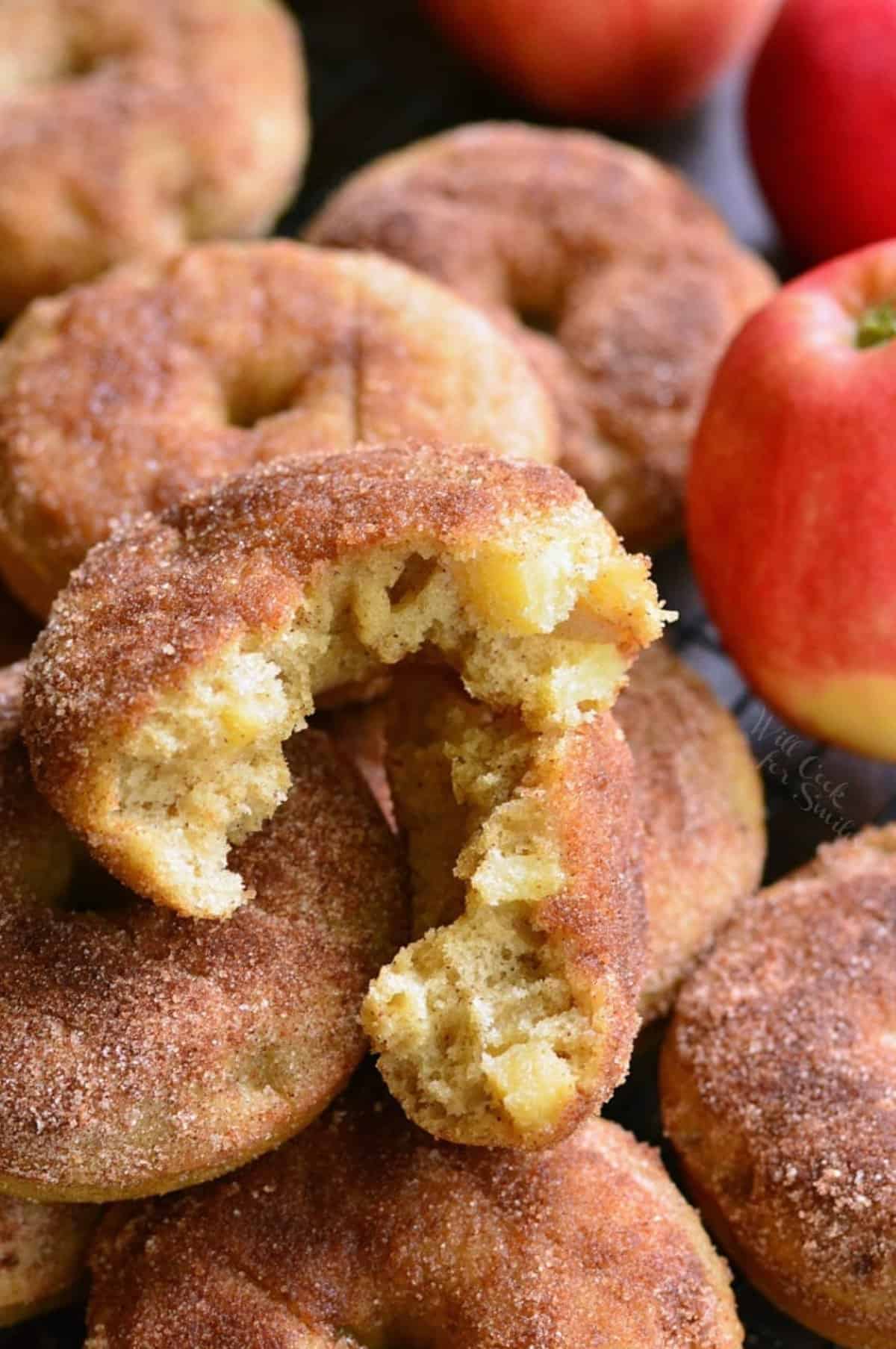 Apple pie donuts with piled up on a wire rack with one torn in apart.