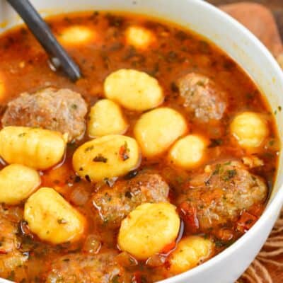 meatball and gnocchi soup in a bowl with a spoon in it.