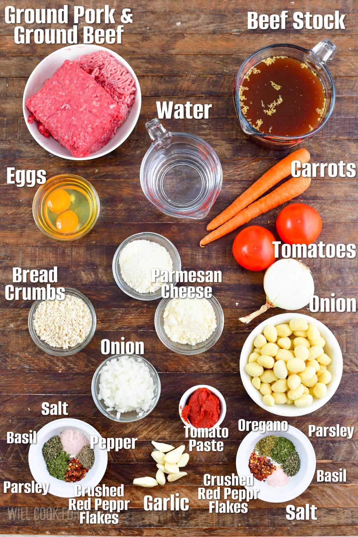 labeled ingredients to make Italian meatball and gnocchi soup on a wooden board.