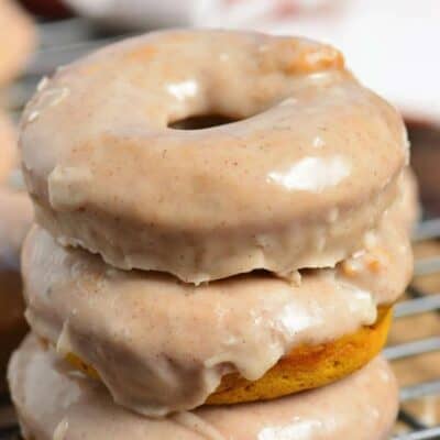 pumpkin donuts stacked up on a wire rack.