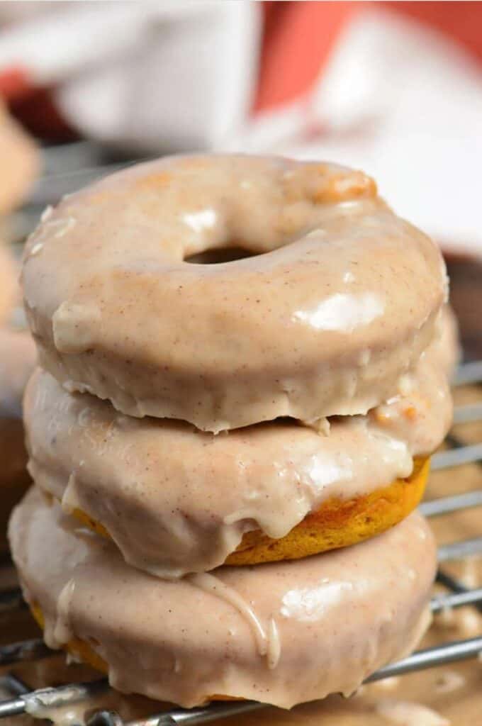 pumpkin donuts stacked up on a wire rack.