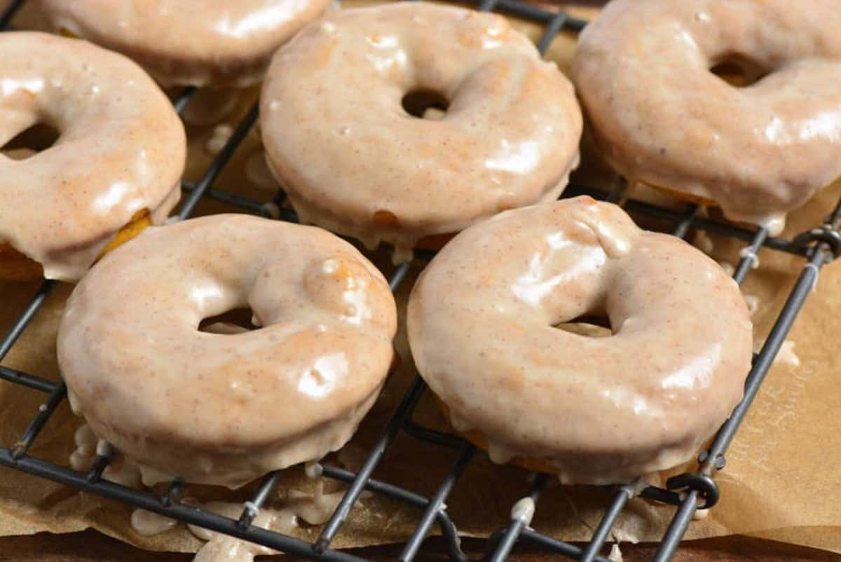 pumpkins donuts that have been dipped in glaze on a wire rack.