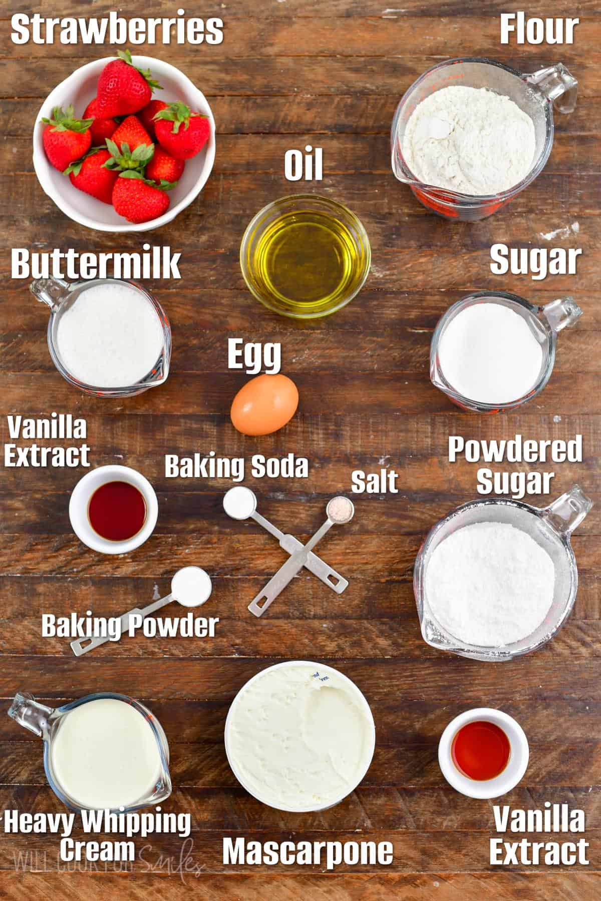 Labeled ingredients for strawberry cupcakes on a wood surface.