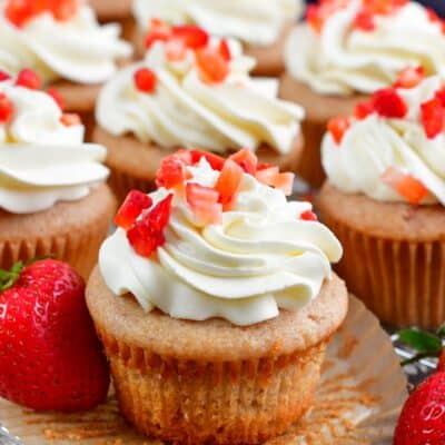 Strawberry Cupcakes on a wire rack with one of the cupcakes unwrapped.