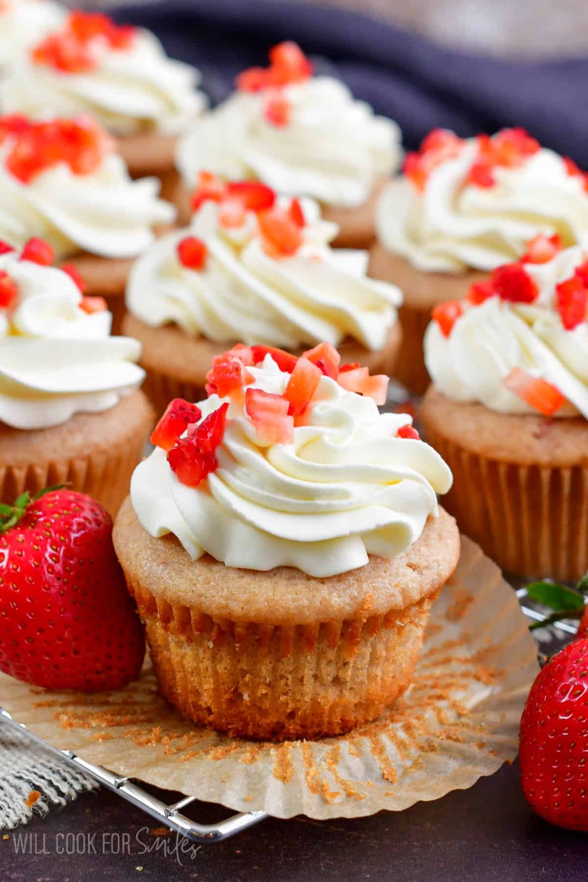 Strawberry Cupcakes on a wire rack with one of the cupcakes unwrapped.