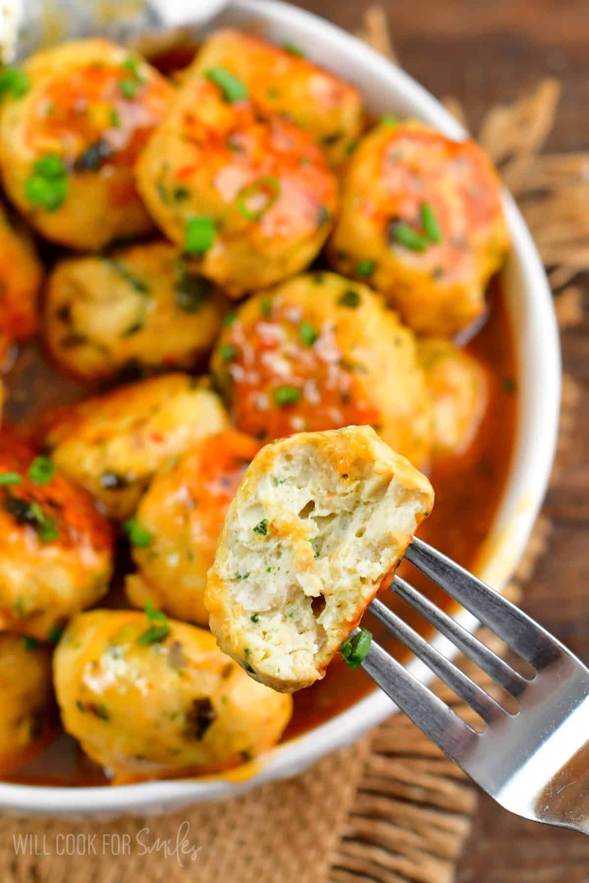 meatball cut in half and on a fork with the rest of the meatballs in a bowl.