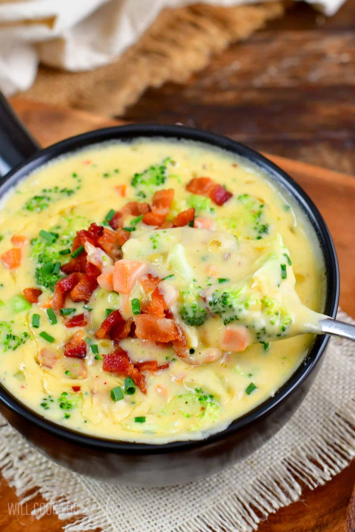 Bacon Broccoli Cheese Soup in a bowl scooping some up with a spoon.