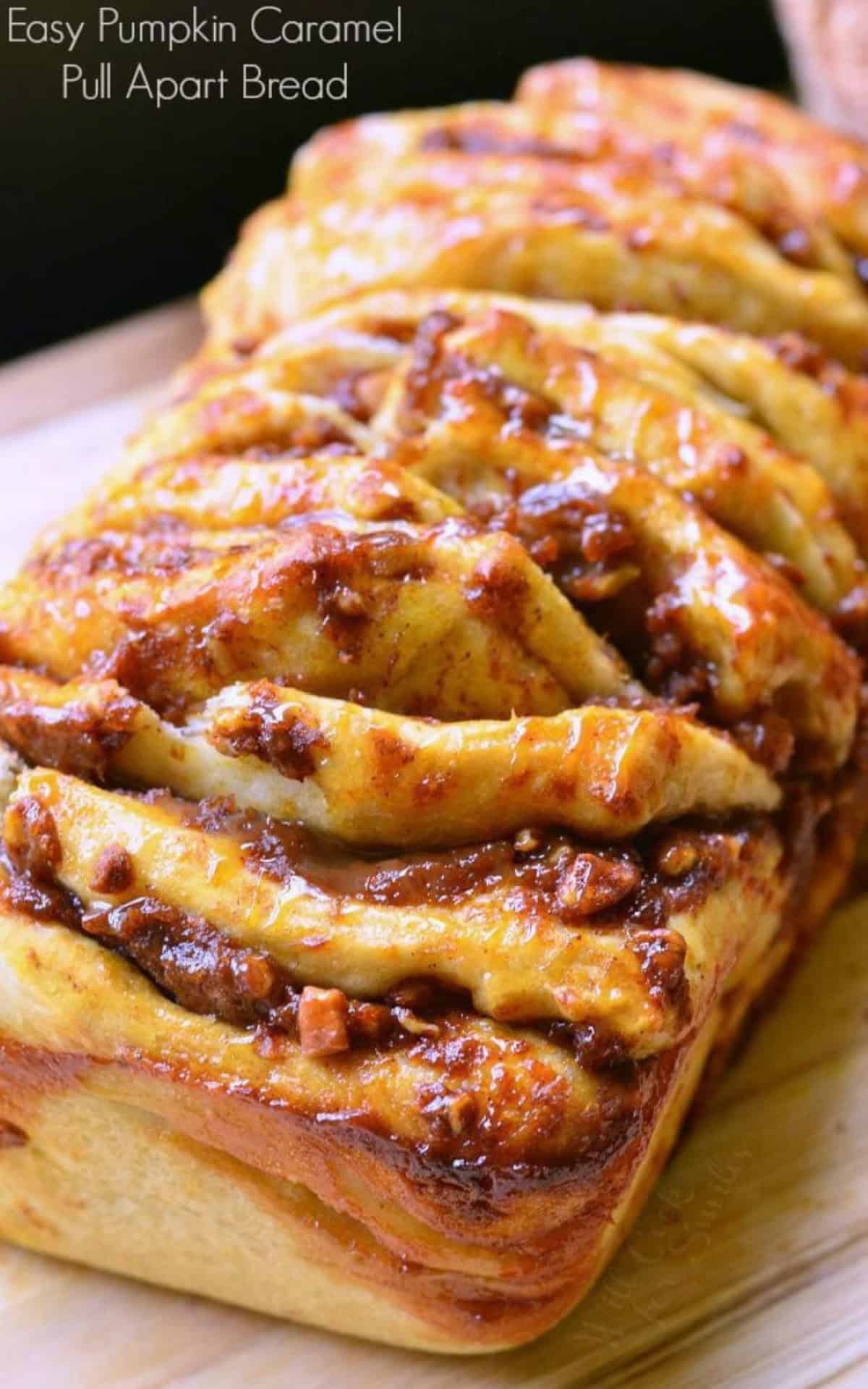 juicy pumpkin pull apart bread with caramel on top on a cutting board and title.