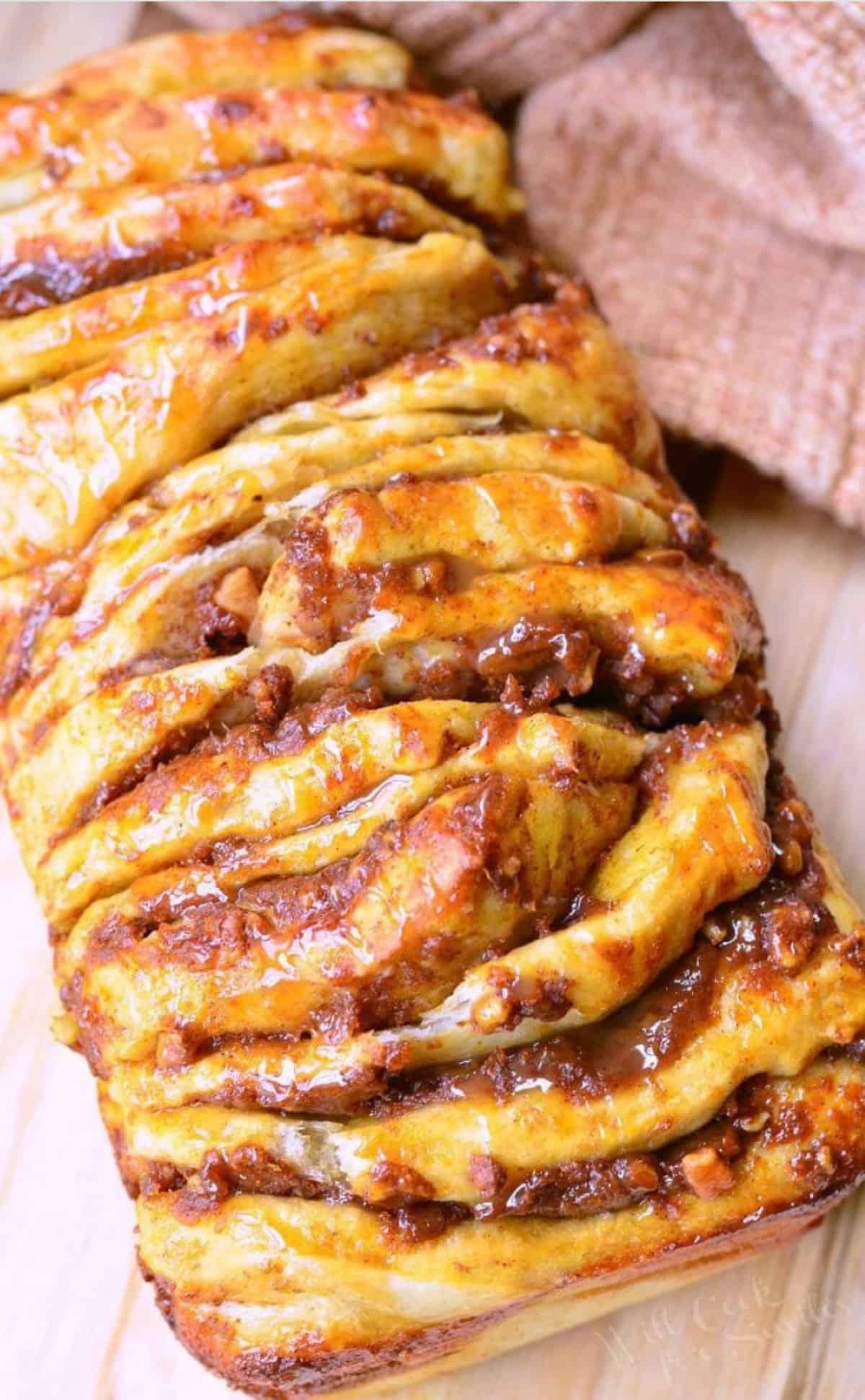 load of pumpkin pull apart bread drizzled with caramel on wooden board.