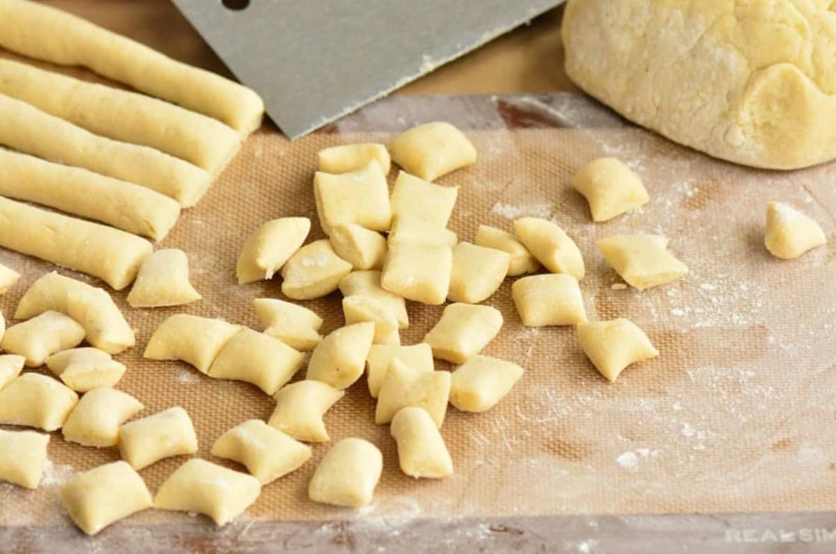 cut strings of dough into pieces of gnocchi on floured surface.