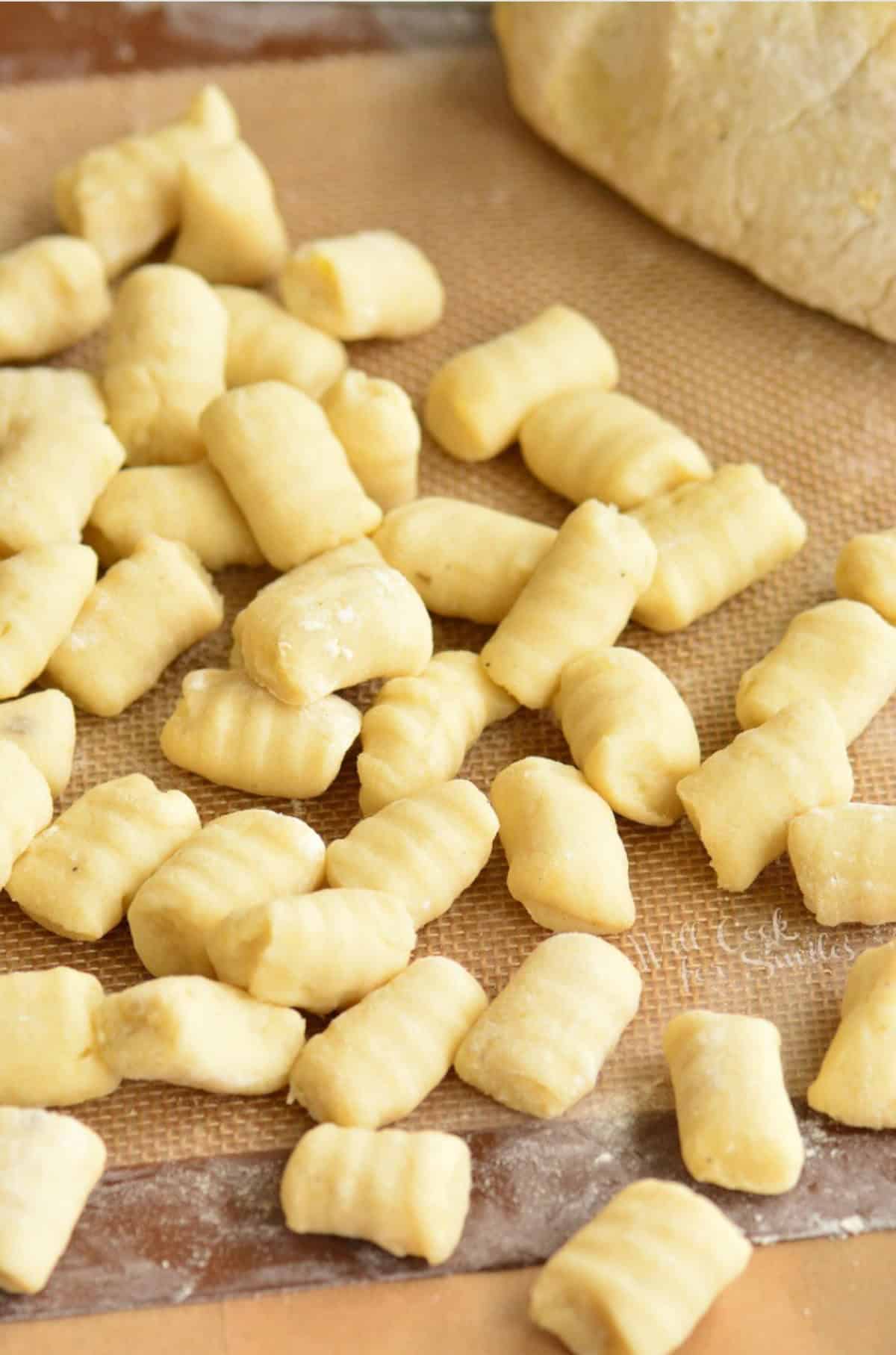 rolled pieces of gnocchi on a silicone mat next to another half of dough.