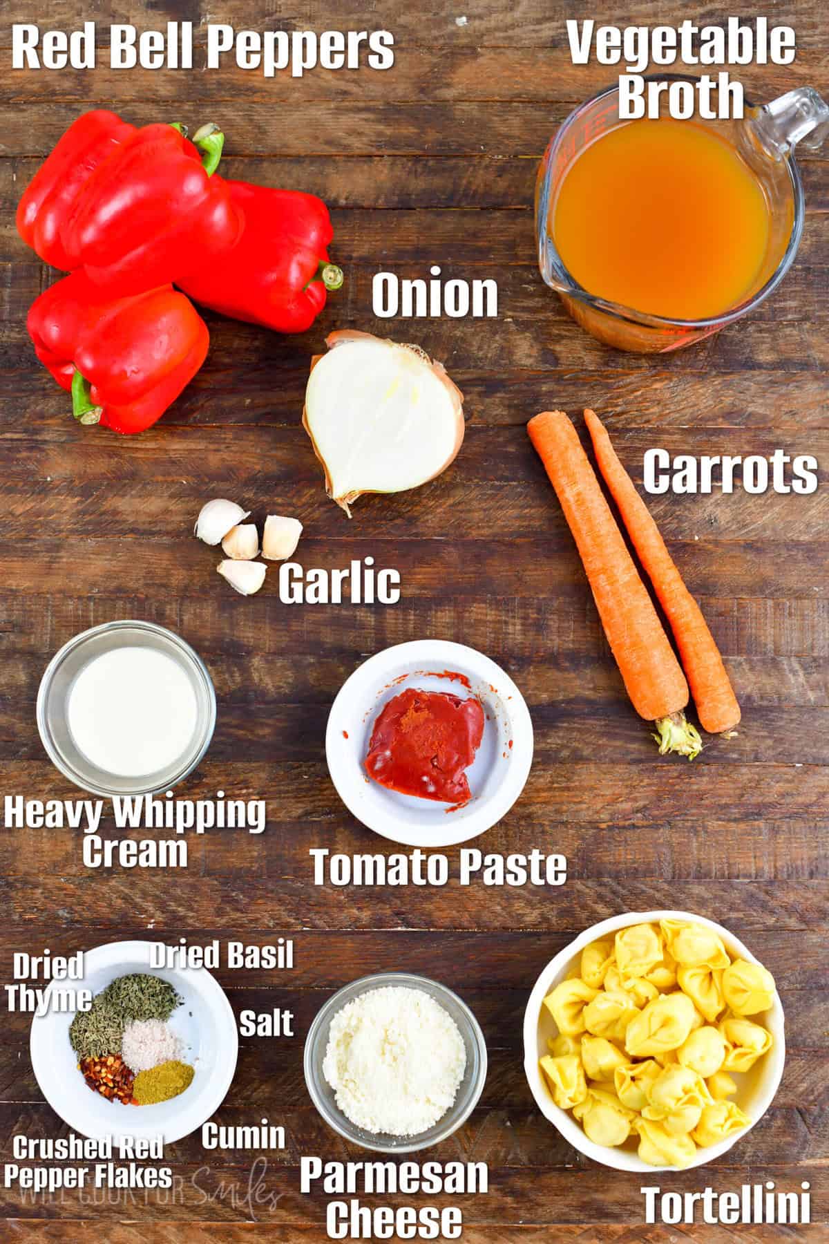 labeled ingredients to make roasted red pepper soup on wooden board.