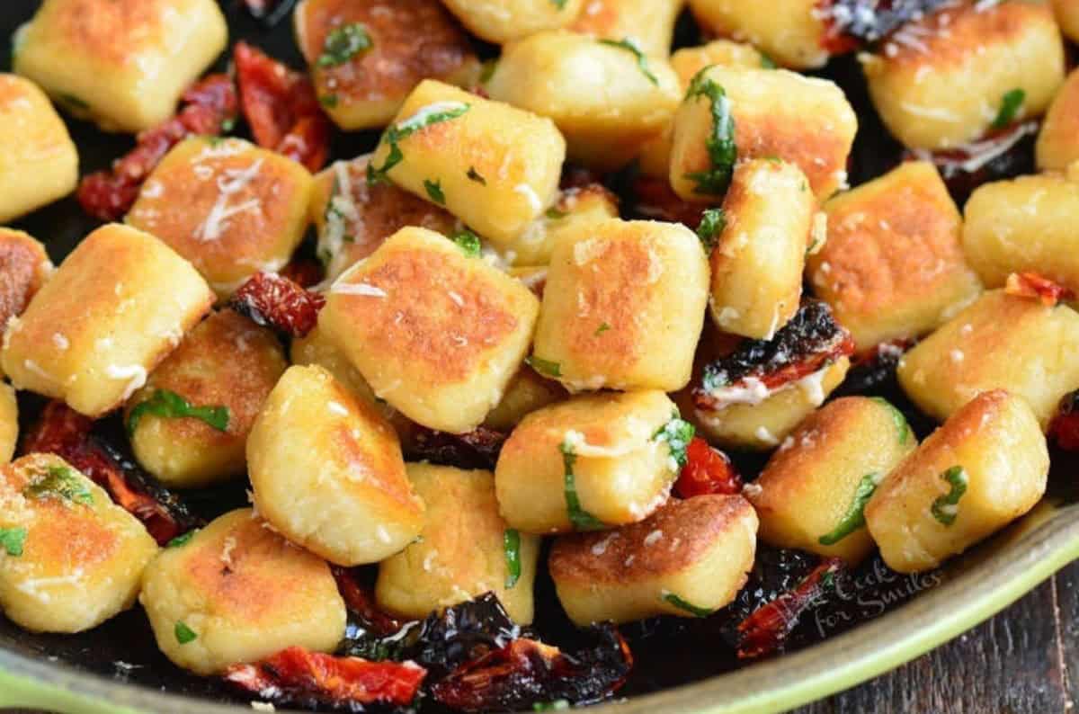 a bowl of seared cauliflower gnocchi with sun dried tomatoes basil and parmesan.