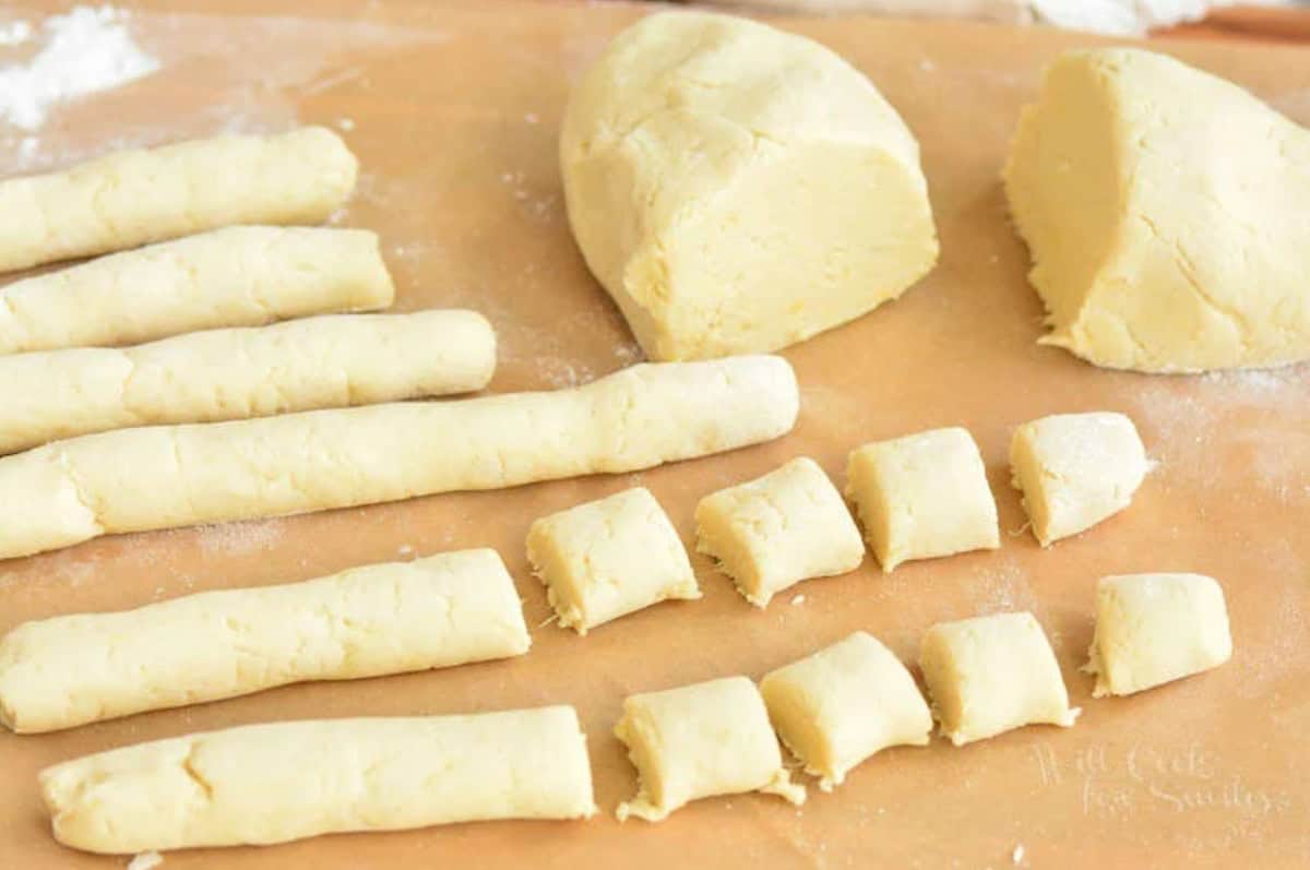 strips of cauliflower gnocchi dough cut into pieces next to more dough.