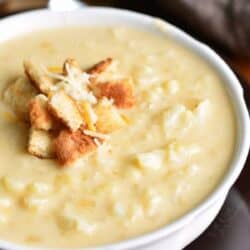 creamy and cheesy cauliflower soup topped with small bread croutons and shredded cheese.