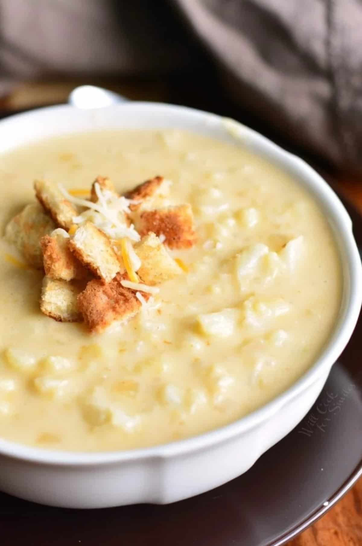 creamy and cheesy cauliflower soup topped with small bread croutons and shredded cheese.