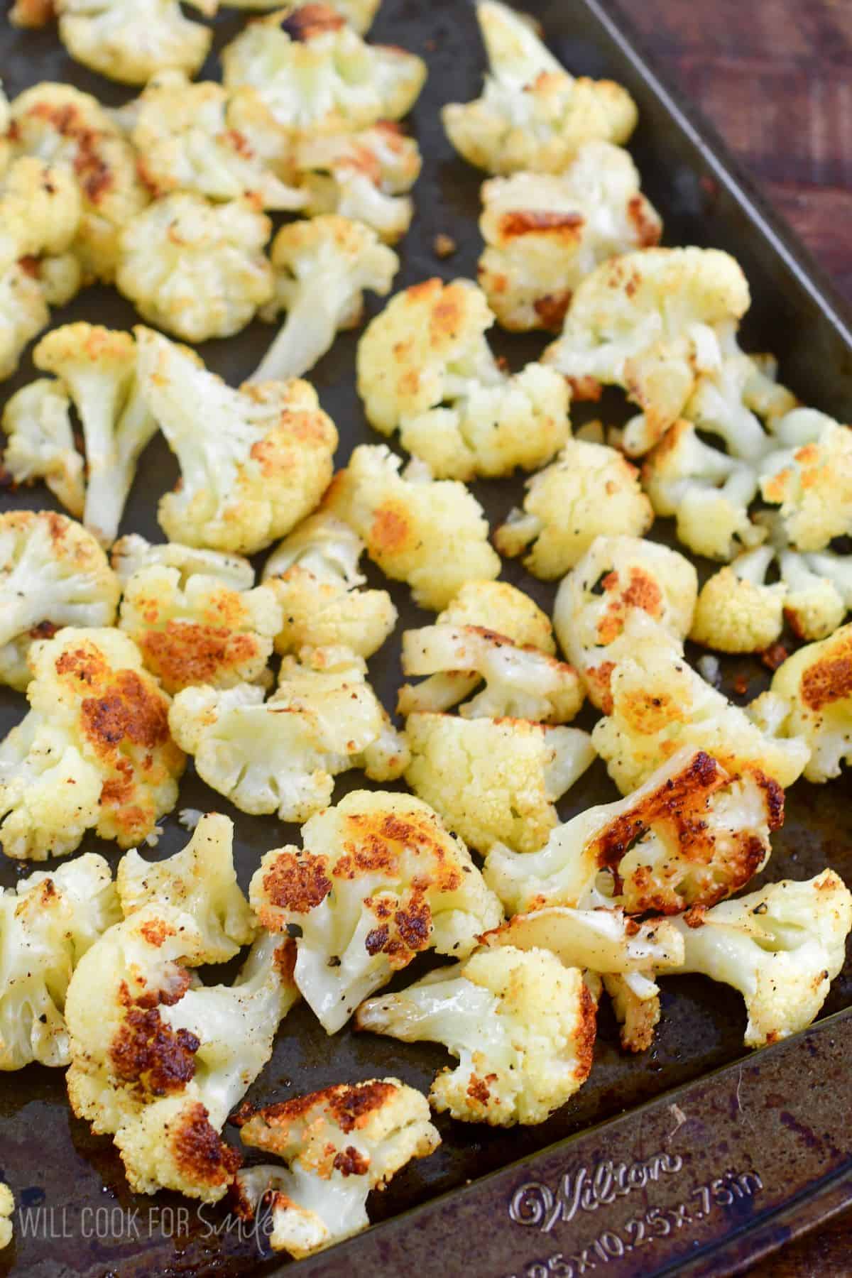 roasted cauliflower florets spread on a baking sheet.