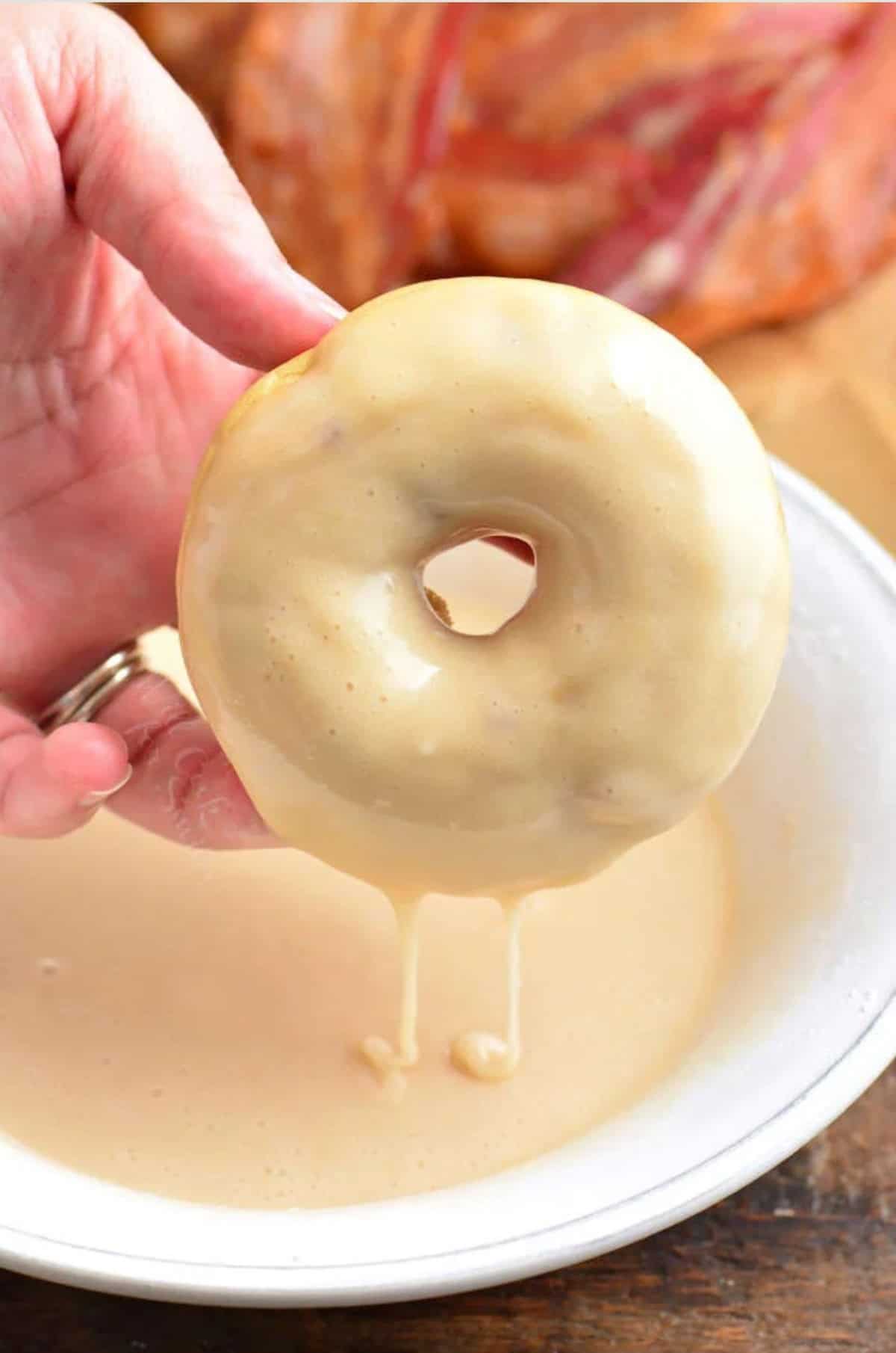 Dipping the maple donut in a bowl of icing.