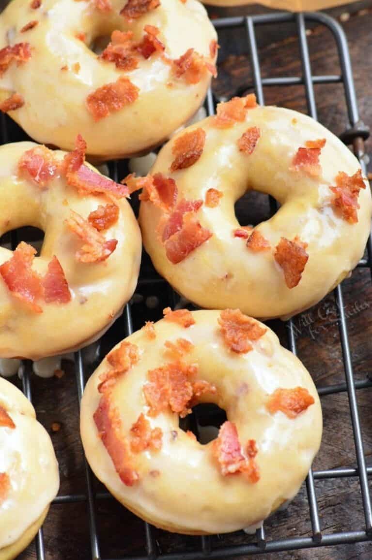 Maple bacon donuts on a wire rack on a wood surface.