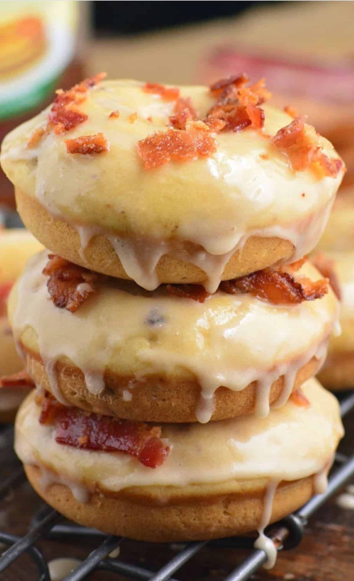 three maple bacon donuts in a stack on a wire rack.