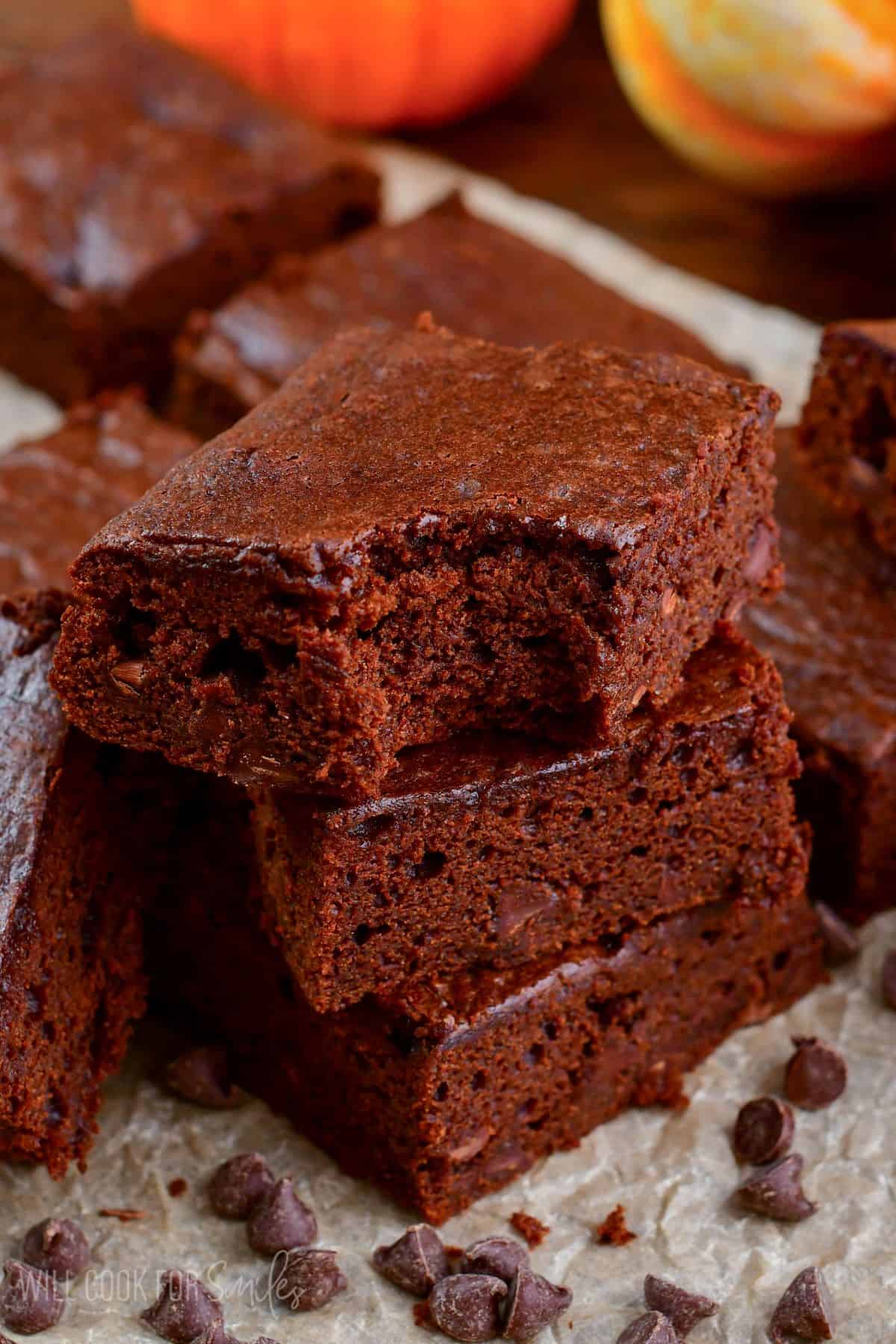 Pumpkin brownies stacked up with the a bite out of the top brownie.