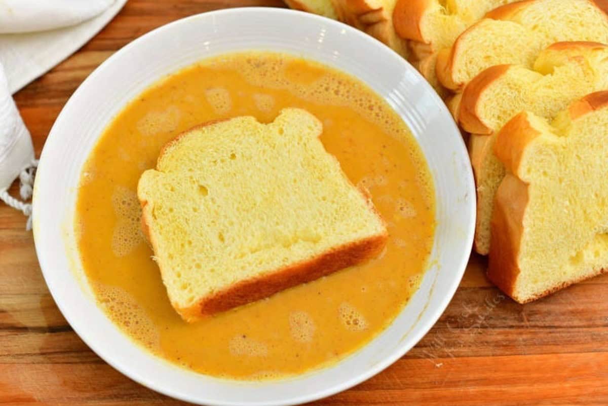 soaking Brioche bread slices in a pumpkin egg mixture.