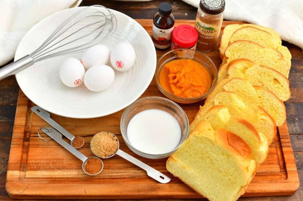 ingredients to make pumpkin French toast on a wooden cutting board.