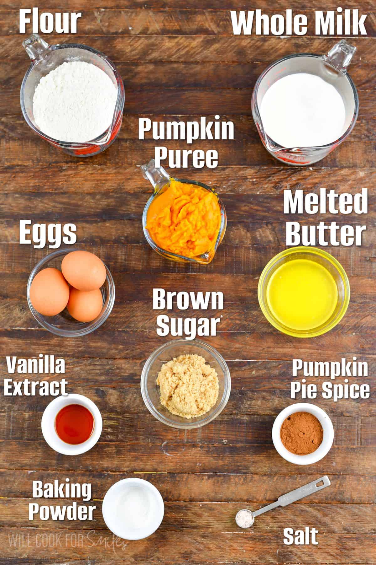 Labeled ingredients for pumpkin waffles on a wood surface.