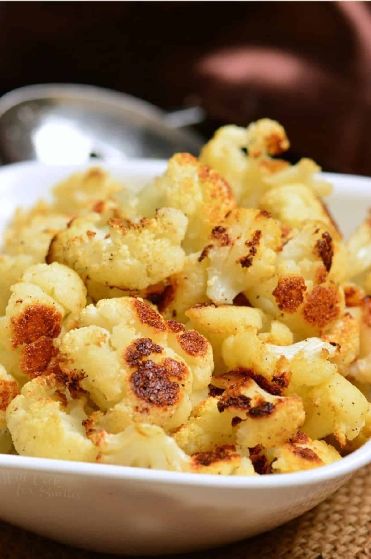 Roasted Cauliflower Florets in a serving bowl on a placemat.