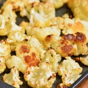 Roasted cauliflower florets on a baking on a wood surface.