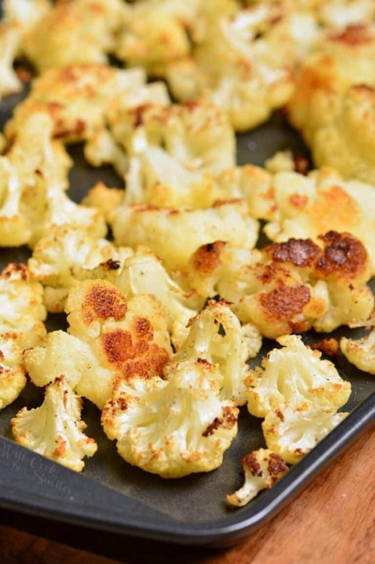 Roasted cauliflower florets on a baking on a wood surface.