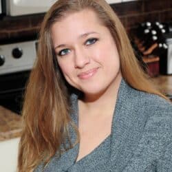 Lyuba Brooke wearing a grey sweater in the kitchen smiling at the camera.