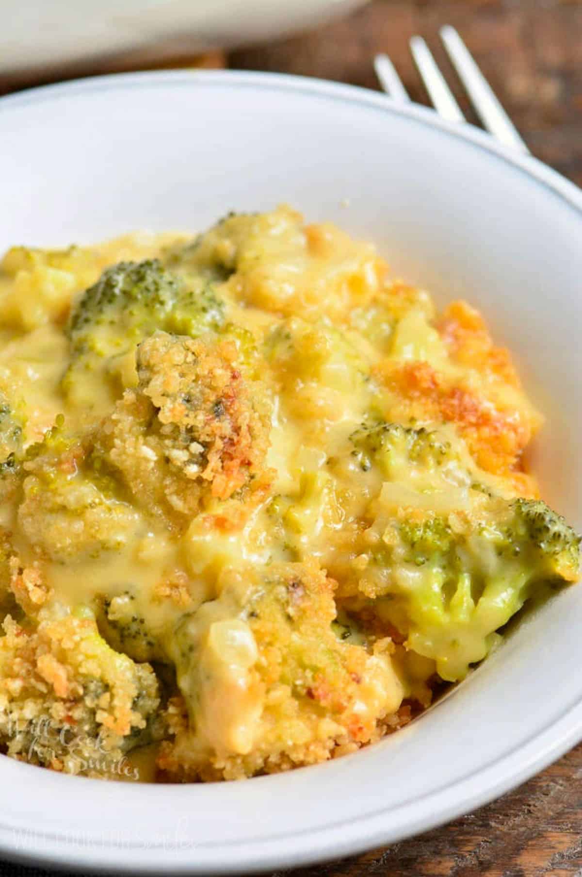 broccoli cheese casserole in a while bowl with a fork.