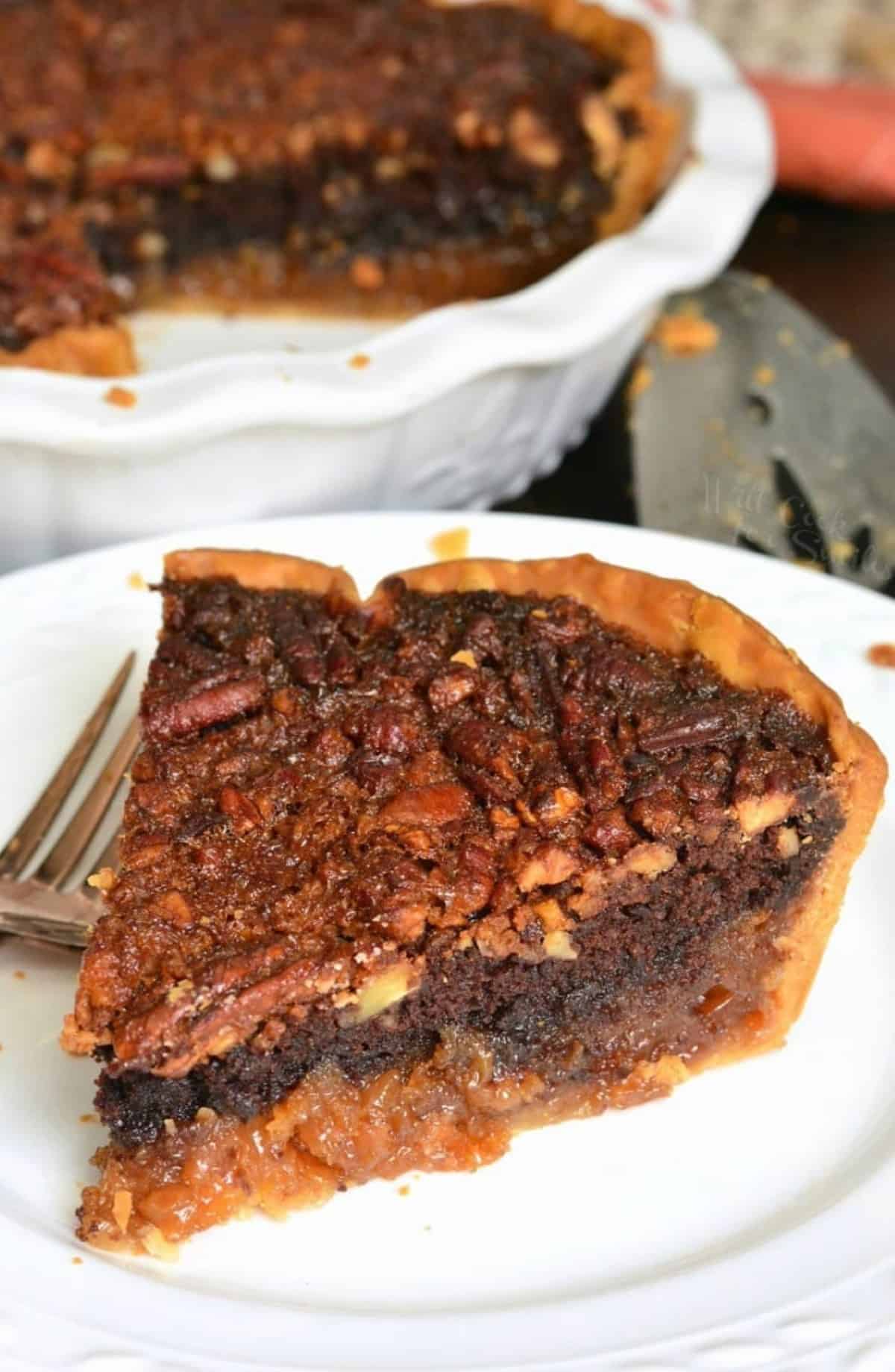 a slice of brownie pecan pie on a plate next to the whole pie dish.