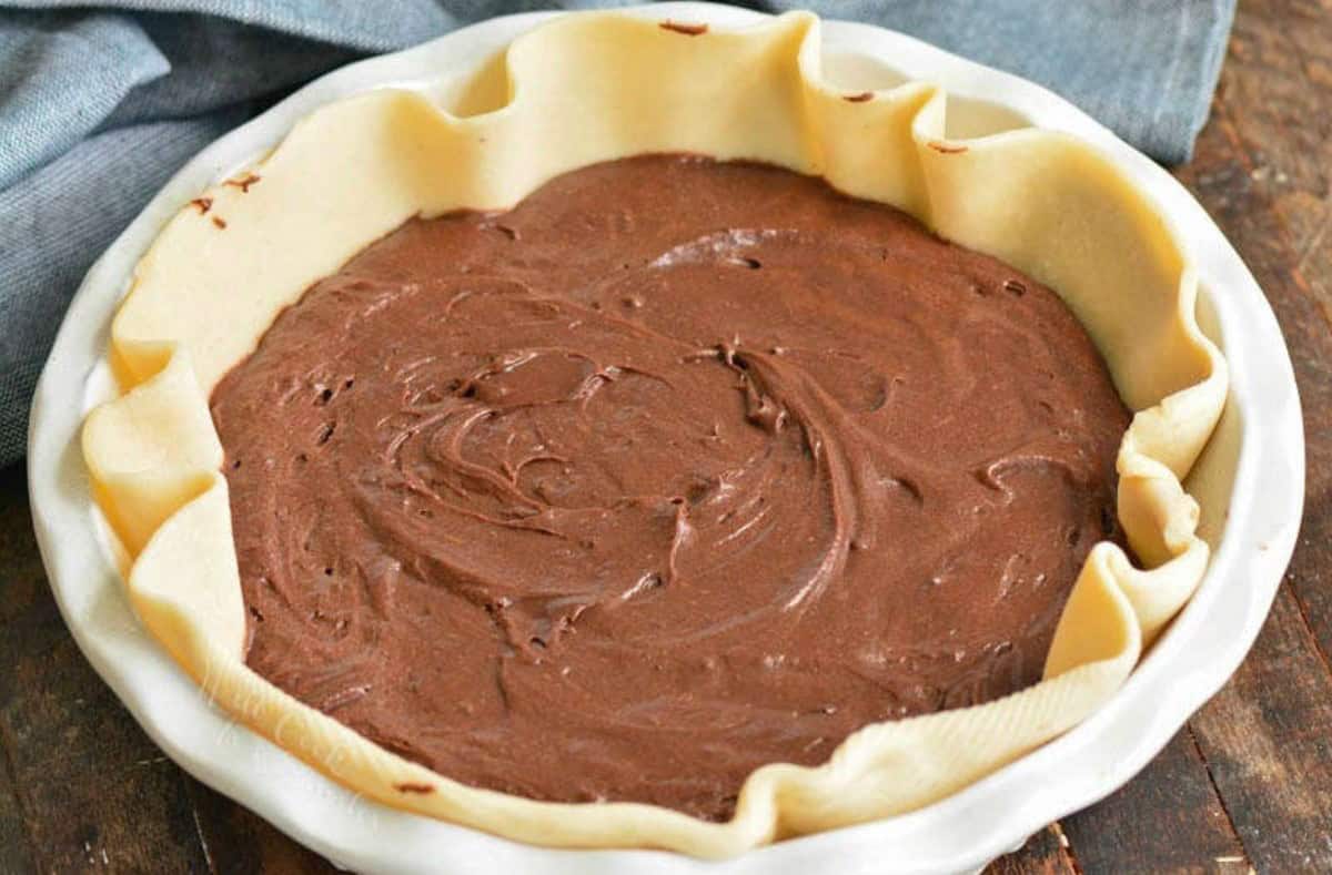 spread brownie batter inside the pie crust in the baking dish.