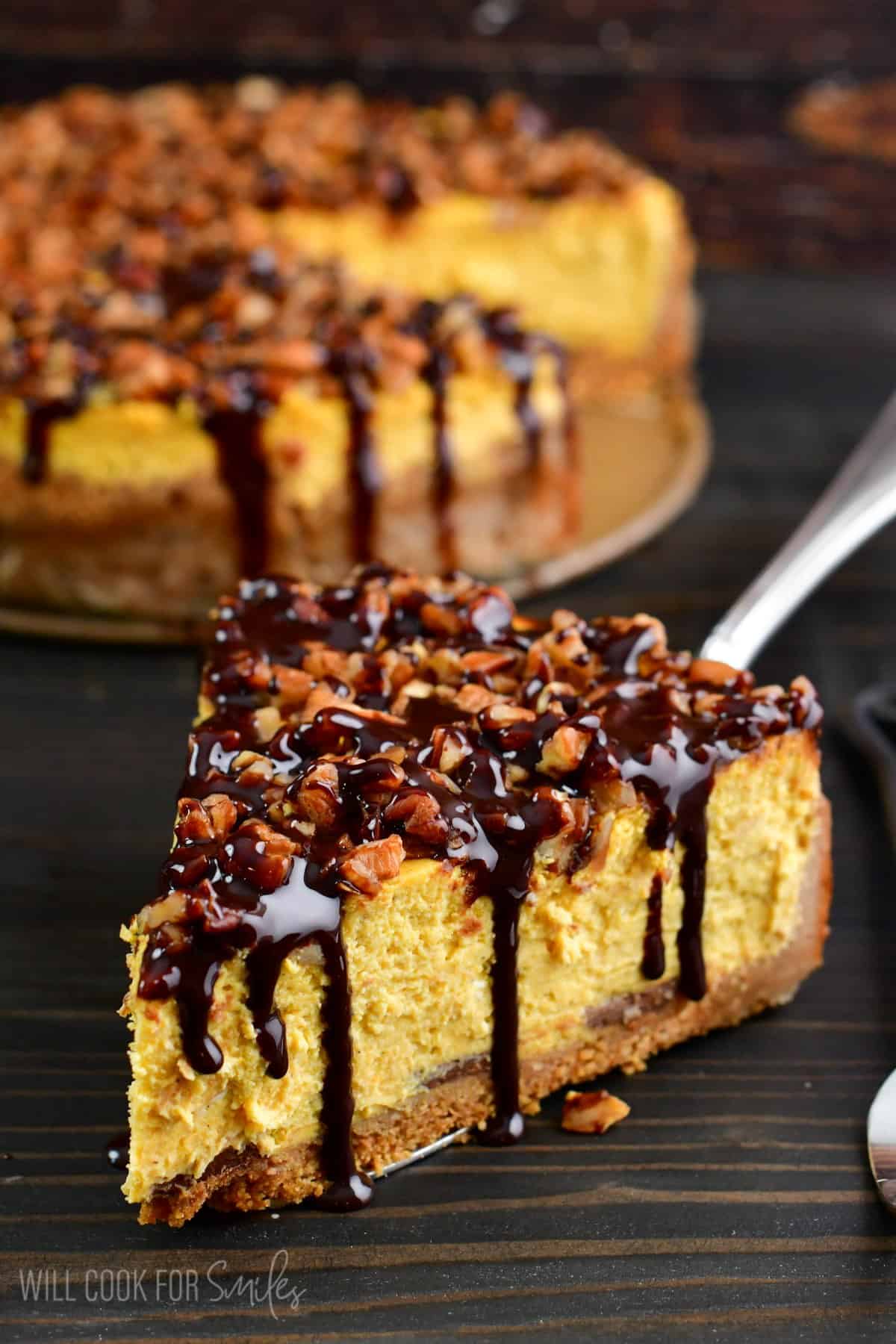 a slice of pumpkin cheesecake topped with pecans and chocolate syrup.